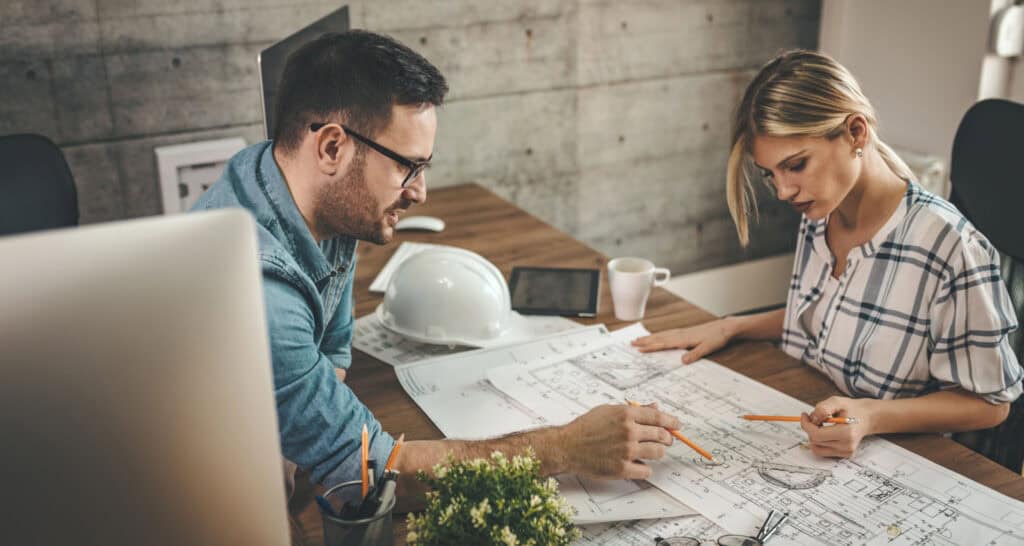 interioristas y arquitectos barcelona, dos arquitectos chico y chica mirando planos